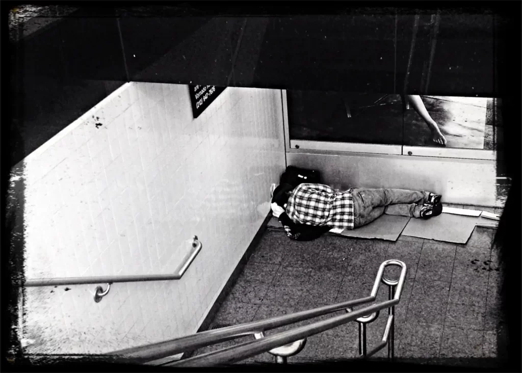 Hemlös ligger i ett trapphus och sover