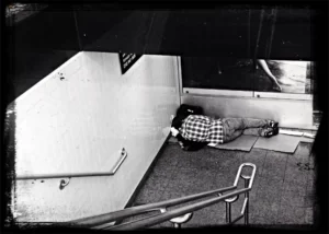 Hemlös ligger i ett trapphus och sover