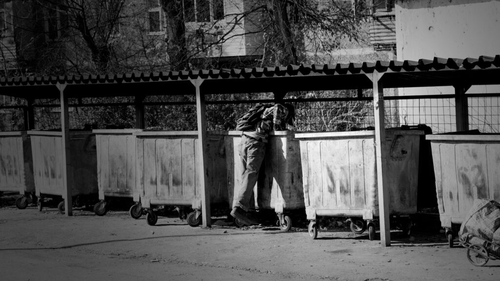 hemlös man letar i sopcontainer