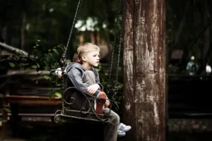 Ett barn sitter i en gunga och funderar