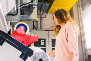 Kvinna står vid en maskin och arbetar