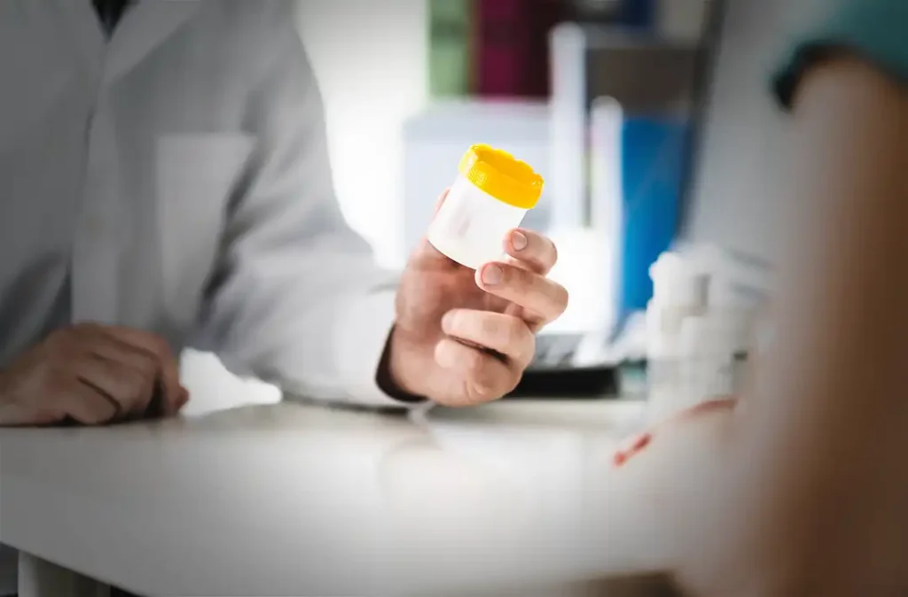 Läkare ger en person ett burk för urinprov