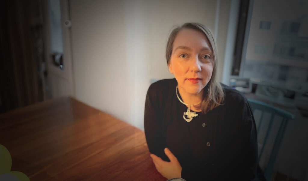 Linnea sitter vid sitt köksbord i sitt hem