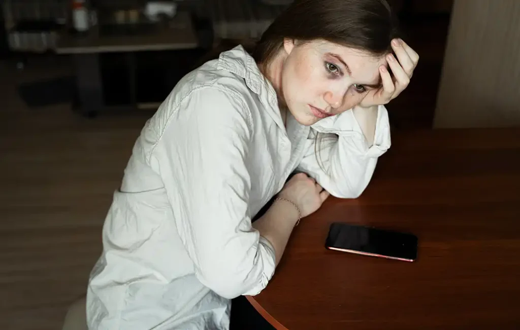 Kvinna överväger om hon ska ringa och anmäla våld i nära relation