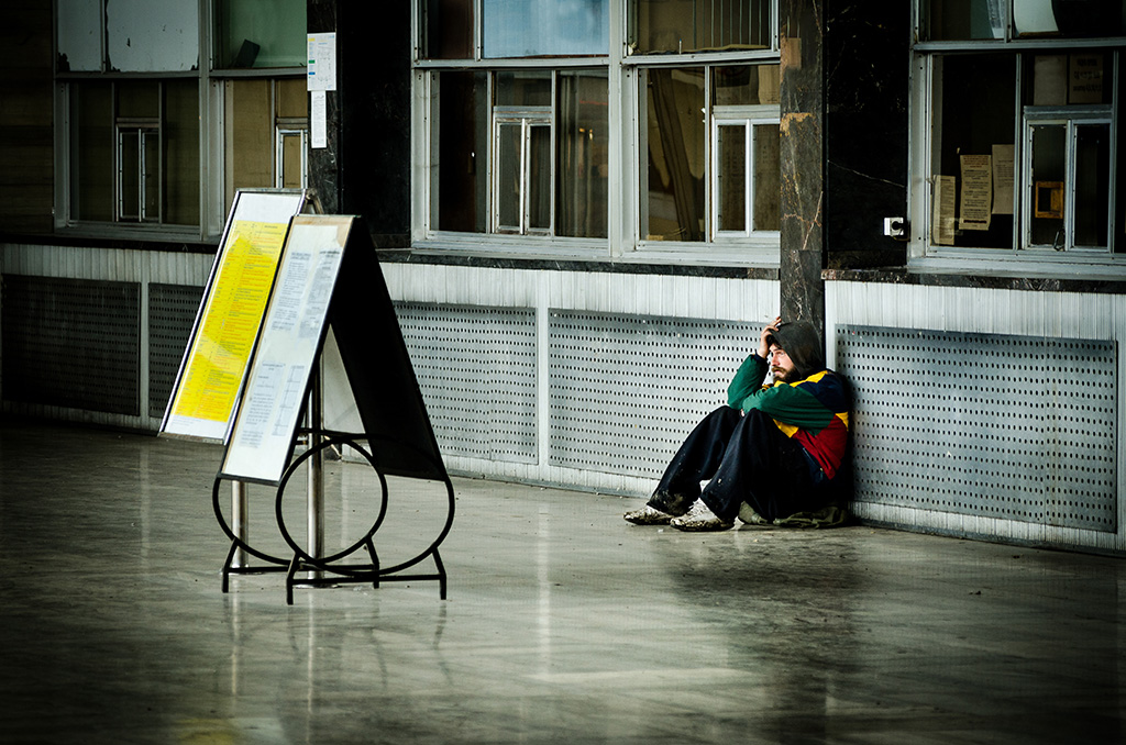 Hemlös man sitter på en centralstation ensam