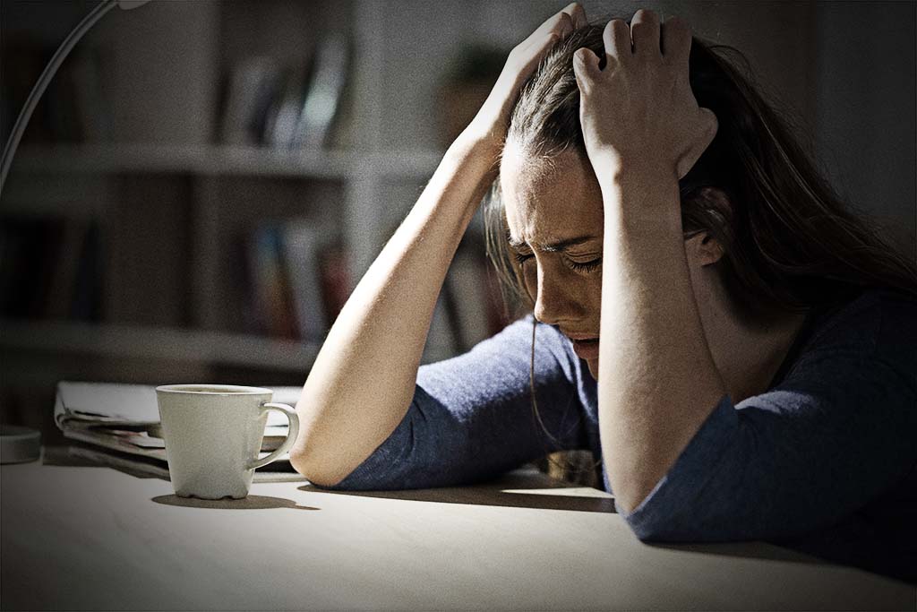 Kvinna, river sitt hår i frustration sittande vid sitt skrivbord