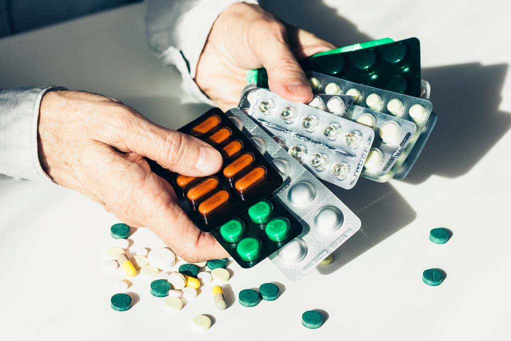 En äldre perosn håller i massor av olika mediciner.
